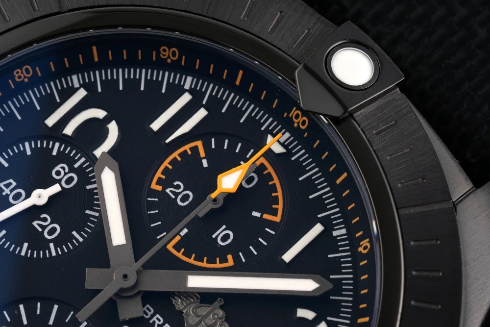 Close-up of Breitling Avenger Chronograph blue Reflective Black dial with orange-accented 30-minute counter and applied hour markers lower