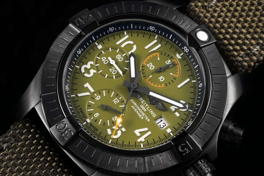 Close-up of Breitling Avenger Chronograph Green dial, white Arabic numerals, Yellow-tipped chronograph hand and date window at 3 o'clock